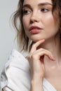 Portrait of young woman on gray background. Female posing in milky white corduroy shirt