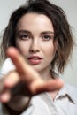 Portrait of young woman with hand stretched forward. Female posing in milky white corduroy shirt