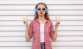 Portrait young woman in headphones listening to music on a white background, cool female model blowing her red lips having fun