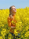 Portrait of a young woman with her eyes closed in a flowering rapeseed field