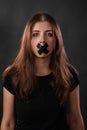 Portrait of a young woman with her mouth sealed with black tape, restriction of freedom of speech, censorship and a ban Royalty Free Stock Photo