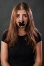 Portrait of a young woman with her mouth sealed with black tape, restriction of freedom of speech, censorship and a ban Royalty Free Stock Photo