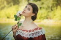 Portrait of a young woman in a historical dress from the 19th century. Beautiful girl with a rose in her hand. Summer background. Royalty Free Stock Photo