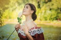 Portrait of a young woman in a historical dress from the 19th century. Beautiful girl with a rose in her hand. Summer background. Royalty Free Stock Photo