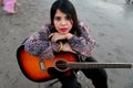 Portrait of a young woman holding an acoustic guitar on a sandy beach looking at the camera with a serious expression Royalty Free Stock Photo