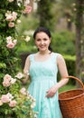 Portrait of young woman holding a basket near roses in a garden Royalty Free Stock Photo