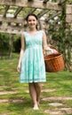 Portrait of young woman holding a basket near roses in a garden Royalty Free Stock Photo