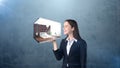 Portrait of young woman holding 3d interior on the open hand palm, over isolated studio background. Business concept.