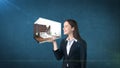 Portrait of young woman holding 3d interior on the open hand palm, over isolated studio background. Business concept.