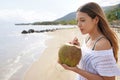 Portrait of young woman holding a fresh green coconut enjoying drinking on the beach Royalty Free Stock Photo