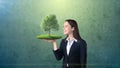 Portrait of young woman holding green tree on the open hand palm, over isolated studio background. Business, eco concept Royalty Free Stock Photo