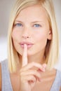 Ill never tell my beauty secrets. Portrait of a young woman holding her finger in front of her lips. Royalty Free Stock Photo