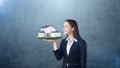 Portrait of young woman holding modern house on the open hand palm, over isolated studio background. Business concept. Royalty Free Stock Photo