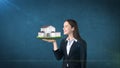 Portrait of young woman holding modern house on the open hand palm, over isolated studio background. Business concept. Royalty Free Stock Photo