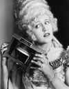 Portrait of a young woman holding one of the first telephones