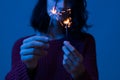 Portrait of young woman holding sparkle stick.