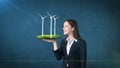 Portrait of young woman holding windmill on the open hand palm, over isolated studio background. Business, eco concept. Royalty Free Stock Photo