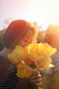 Portrait of a young woman inhales the scent of spring flowers, yellow tulips. Concept of Allergy. Vertical Royalty Free Stock Photo