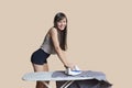 Portrait of a young woman ironing shirt over colored background Royalty Free Stock Photo