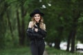 Portrait of a young woman in leather jacket and black hat walking alone on a summer city street Royalty Free Stock Photo