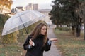 Portrait of young woman with long brown hair standing outside and holding umbrella. Girl with an umbrella on cloudy autumn day Royalty Free Stock Photo