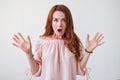 Portrait young woman with long curly red hair looking excited holding her mouth opened isolated on white wall. Royalty Free Stock Photo