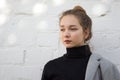 Portrait of young caucasian woman looking aside with calm look on white brick background