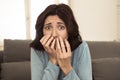 Portrait of a young woman looking scared and shocked watching scary movie on TV Royalty Free Stock Photo