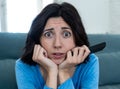 Portrait of a young woman looking scared and shocked watching TV. Human expressions and emotions Royalty Free Stock Photo