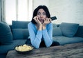 Portrait of a young woman looking scared and shocked watching TV. Human expressions and emotions Royalty Free Stock Photo