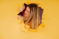 Young woman looking through a torn hole in paper wall. Royalty Free Stock Photo