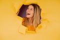 Young woman looking through a torn hole in paper wall. Royalty Free Stock Photo