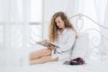 Young woman lying on the bed while reading a book, relaxing time Royalty Free Stock Photo