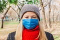 Portrait of a young woman in a medical mask who walks in the park alone in winter. Social distance. Coronavirus concept