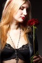 Portrait of young woman model in red dress holding red rose flower in hand over dark background in photo studio. Beauty Royalty Free Stock Photo