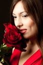 Portrait of young woman model in red dress holding red rose flower in hand Royalty Free Stock Photo