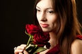 Portrait of young woman model in red dress holding red rose flower in hand Royalty Free Stock Photo