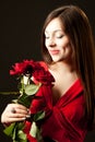 Portrait of young woman model in red dress holding red rose flower in hand Royalty Free Stock Photo