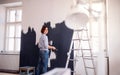 A portrait of young woman painting wall black. A startup of small business. Royalty Free Stock Photo