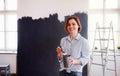 A portrait of young woman painting wall black. A startup of small business. Royalty Free Stock Photo