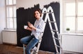 A portrait of young woman painting wall black. A startup of small business. Royalty Free Stock Photo