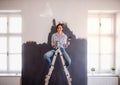 A portrait of young woman painting wall black. A startup of small business. Royalty Free Stock Photo