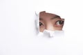 Portrait of young woman peeking through a ripped paper hole Royalty Free Stock Photo