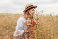 Portrait of young woman picking wildflowers in summer meadow smelling bouquet of poppies and daisies