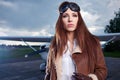 Portrait of young woman pilot in front of airplane. Royalty Free Stock Photo