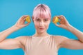 Portrait of young woman with pink hair smiling and holding halves of fresh lemon near her ears, posing  over Royalty Free Stock Photo