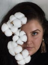 Portrait of young woman plus size with brown hair and intent look with branch of fluffy cotton near to her face