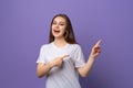 Portrait of young woman pointing fingers aside and looking with positive face expression, standing over purple background Royalty Free Stock Photo