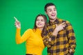 Portrait of young woman pointing at something ahead isolated on green background, her boyfriend is looking at something Royalty Free Stock Photo