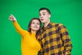 Portrait of young woman pointing at something ahead isolated on green background, her boyfriend is looking at it Royalty Free Stock Photo